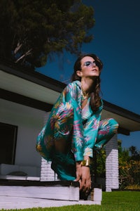 a woman is crouching on a ledge in front of a house