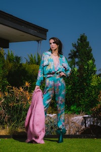 a woman in a floral jumpsuit standing in front of a house