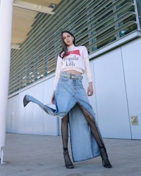 a woman wearing a denim skirt and a white t - shirt