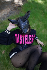 a woman laying on the grass wearing a tasteless mask