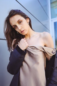 a woman in a tan top posing in front of a building