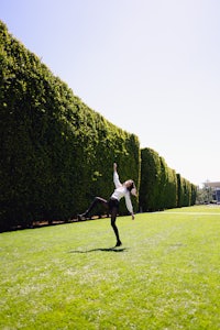 a woman is flying a frisbee in a grassy field