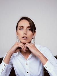 a woman wearing a white shirt and earrings