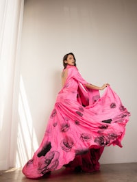 a woman in a pink dress posing in front of a white wall