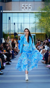 a model walks down the runway in a blue dress