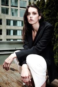 a woman wearing a black jacket and white pants
