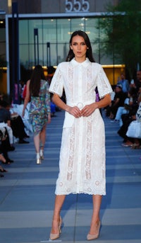 a model wearing a white dress on the runway