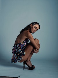 a woman crouching down in a high heeled dress