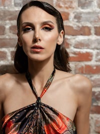 a woman in a red and black dress posing against a brick wall
