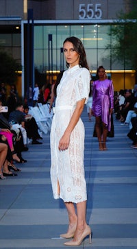 a woman in a white dress walking down the runway
