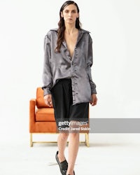 a model wearing a grey shirt and black shorts walks down the runway during fashion week spring/summer 2017 in london,