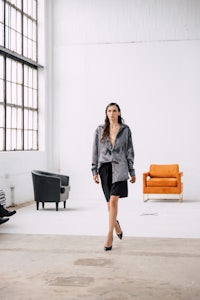 a woman walking in an empty room with couches and chairs