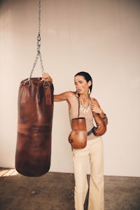 a woman holding a leather boxing bag