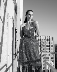 a woman in a sequin dress posing on a balcony