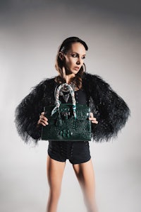 a woman holding a green crocodile bag