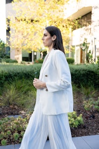 a woman wearing a white blazer and white pants