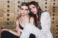 two women posing in front of a gold box