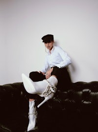 a woman sitting on a black couch with white high heeled boots
