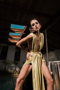 a woman in a yellow dress posing by a pool