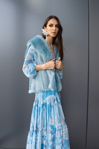 a model in a blue dress and fur vest