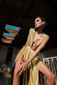a woman in a yellow dress posing next to a pool