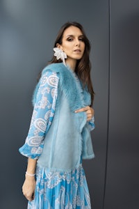a woman wearing a blue fur vest and blue dress