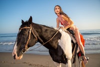 a woman riding a horse on the beach