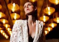 a woman is posing in a white lace blazer