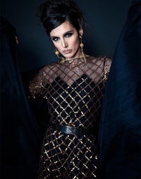 a woman in a black and gold dress posing