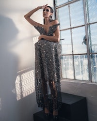 a woman in a sequined dress posing in front of a window