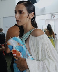 a woman in a white dress holding a blue purse