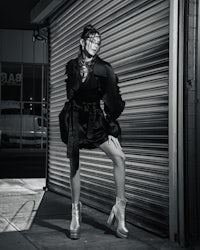 a black and white photo of a woman posing in front of a garage